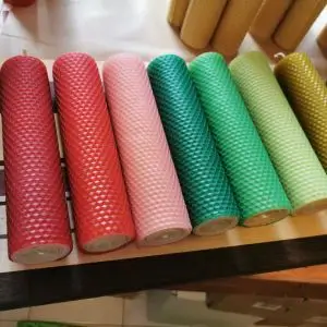 A row of colorful hand-rolled beeswax candles from 