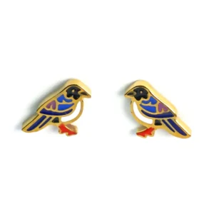 Charming gold pigeon stud earrings by Michelle Stephen, adorned with enamel detailing in blue, black, purple, and white, with striking red feet, captured in a flat lay style.