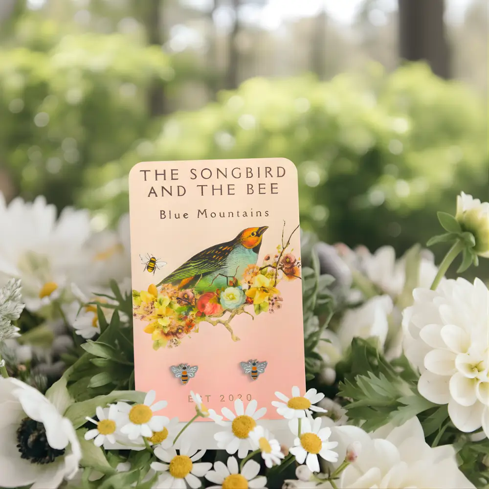 bee silver earrings on a card on a bundle of flowers