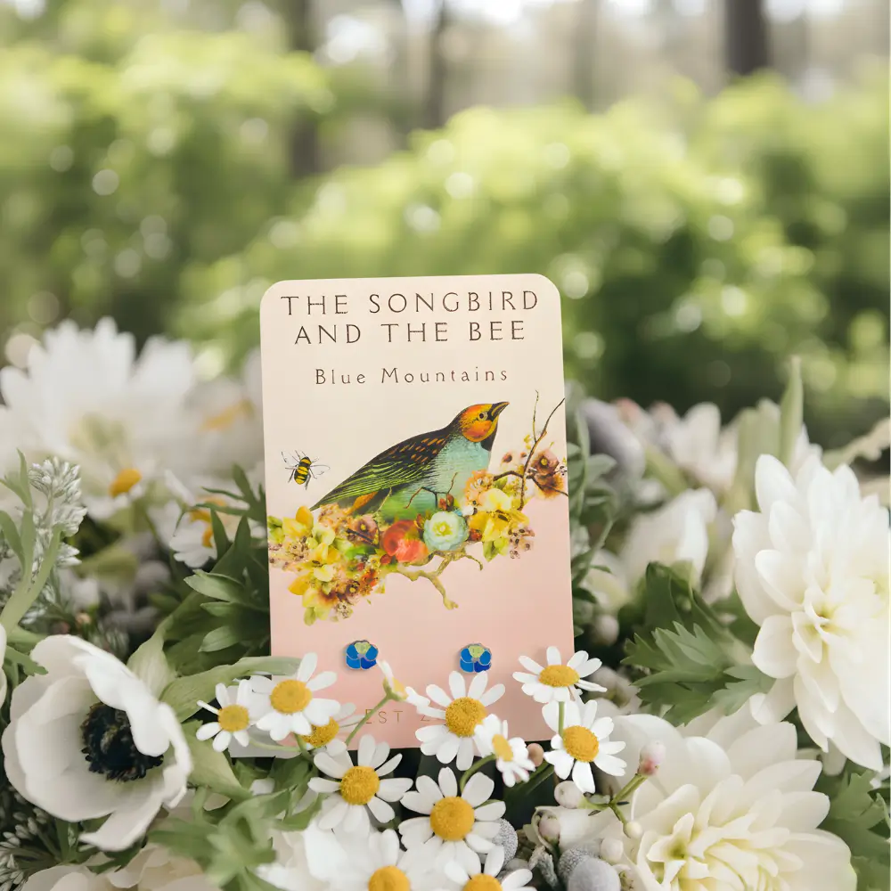 blue flower silver earrings on a card on a bundle of flowers