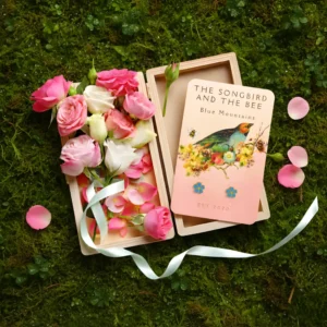 forget me not gold earrings on a card on a box filled with roses on placed on top of mossy ground