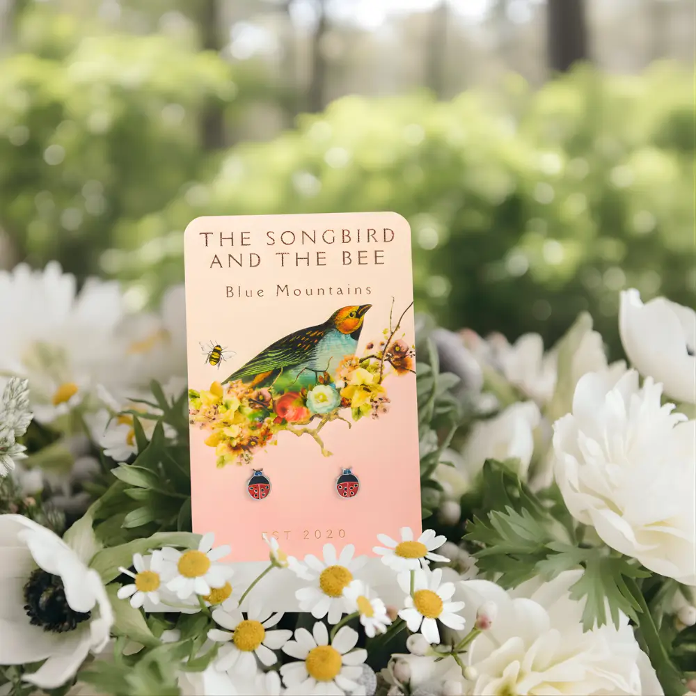 ladybug silver earrings on a card on a bundle of flowers